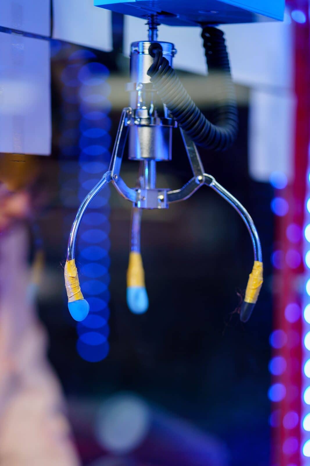 A claw machine's claw glowing under blue neon light